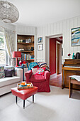 Wood-panelled room with piano, bookshelf and red accents
