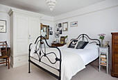 Wrought iron bed and antique wardrobe in white bedroom