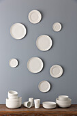 Geschirrstapel und weiße Teller an grauer Wand