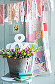 Bucket of Easter tulips with homemade fabric bunting and vinatge quilt