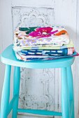 Brightly coloured tea towels on blue stool