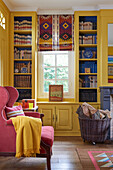 Gelber Bücherschrank und rosa Sessel im Wohnzimmer eines französischen Landhauses