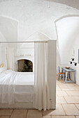 Doppelbett mit Baldachin in schlichtem, weißem Schlafzimmer