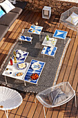 Set table with hors d'oeuvres, blue and white side tables and seating on a terrace