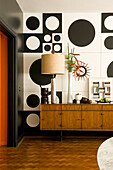 Sideboard im Wohnzimmer im 60er-Jahre Stil mit schwarz-weißer Wanddekoration