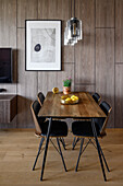 Dining table and four chairs next to wood panelling in open-plan interior