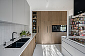 Customised kitchen with wooden fronts and grey fronts in open-plan interior