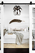 Double bed with a dried palm branch and chandelier with palm tree motif above the bed