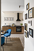 Dining area with blue upholstered chairs in front of small kitchenette