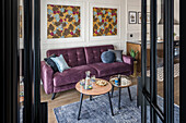 Blick durch geöffnete Glastüren auf lila Sofa und Couchtisch-Set in offenem Wohnraum