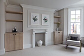 Seating area next to disused fireplace flanked by wooden cabinets and shelves in elegant room