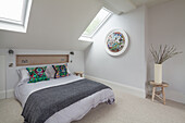 Double bed, wall niche above with wood panelling in light bedroom with skylight windows