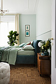 Double bed in blue-green shades and houseplants in bedroom
