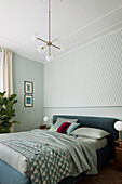 Double bed in blue-green tones in the bedroom with matching wallpaper