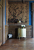 Antique cupboard in a room with large-format tapestry and wood paneling