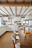 White kitchen with wooden dining table in a converted barn