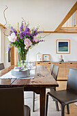 Bouquet of flowers on dining area and leather chairs in converted barn