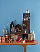 Weihnachtslandschaft als Adventskalender auf Holzkonsole vor blauer Wand