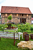 Rural sitting area with earthenware pots with a view of the farm garden and barn