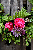 Wreath of ferns with flowers of ranunculus and filled lentil rose