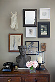 Various artworks on and above antique wooden chest of drawers