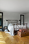 Double bed flanked by wall mirrors in bedroom with oak parquet flooring