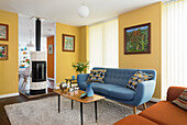 Blue upholstered sofa and coffee table in the seating area with yellow walls, passageway with fireplace