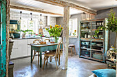 Modern kitchen cabinets and flea market items in a robust kitchen with concrete floor and wooden supporting beams