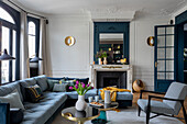 Living room with blue corner sofa and golden wall lamps