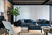 Living room with dark blue sofa, light-coloured armchair and houseplant