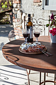 Bottle of wine, wine glasses, and wooden serving board with antipasti in the garden