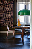 Dining area with dark wooden table, pendant lamp in green and patterned wall hanging