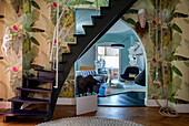 Staircase, floral wallpaper and view of living room with light blue walls