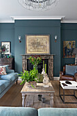 Holztisch und Sitzmöbel vor Kamin im Wohnzimmer mit einer blauen Wand