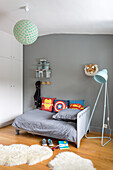 Boy's bedroom with a toddler bed, wardrobe, floor lamp, and animal fur rug