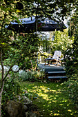 Terrassenplatz mit Sonnenschirm im üppig bewachsenen Garten