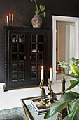 Black display cabinet with candles and houseplants in the living room