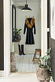 Eingangsbereich mit Mantel an Garderobe, Pflanzen und rustikalem Hocker