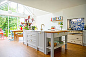 White kitchen island with a butcher block in a bright, open kitchen with a glass floor to ceiling window