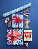 Wrapped gifts decorated with pompom trim and tassels, roll of wallpaper and decorative objects