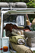 Voll gepackter Geländewagen mit Teppich, Kissen und Campingausrüstung