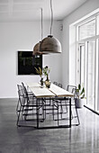 Metal chairs at the dining table made of two boards in an industrial style dining room