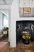 Rustic fireplace area with terracotta floor and vase of flowers