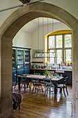 Dining area with arched window, wooden furniture and dark display cabinet