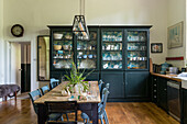 Dining room with rustic wooden table and black display cabinet