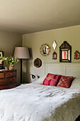 Bedroom with antique chest of drawers and various mirrors on the wall