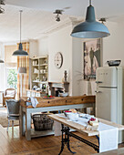 Country-style kitchen with wooden table, retro fridge and blue pendant lights