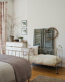Landhaus-Schlafzimmer mit Metallbett, Kinderbett und dekorativen Fensterläden