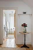 Hallway with wooden table and hydrangea bouquet, with a view into the bathroom
