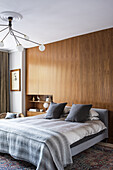 Minimalistisches Schlafzimmer mit Holzpaneelwand und moderner Pendelleuchte
